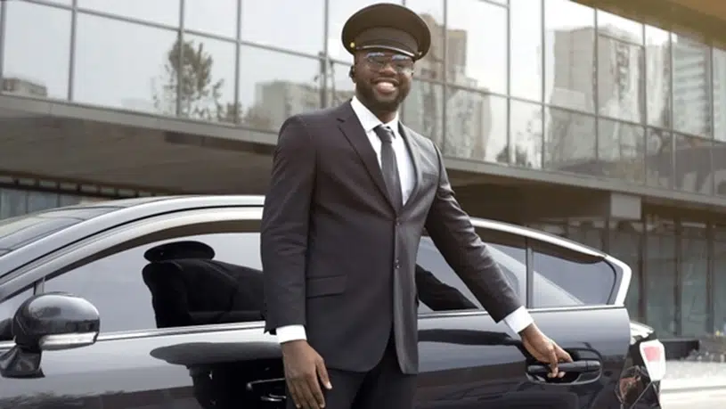 Professional chauffeur standing beside a private transfer car
